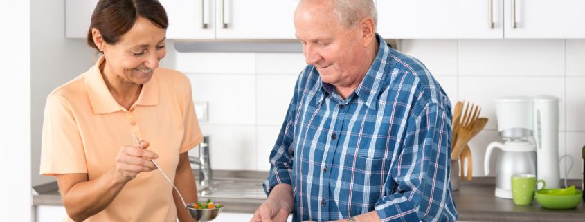 Opiekunka pomaga seniorowi w kuchni
